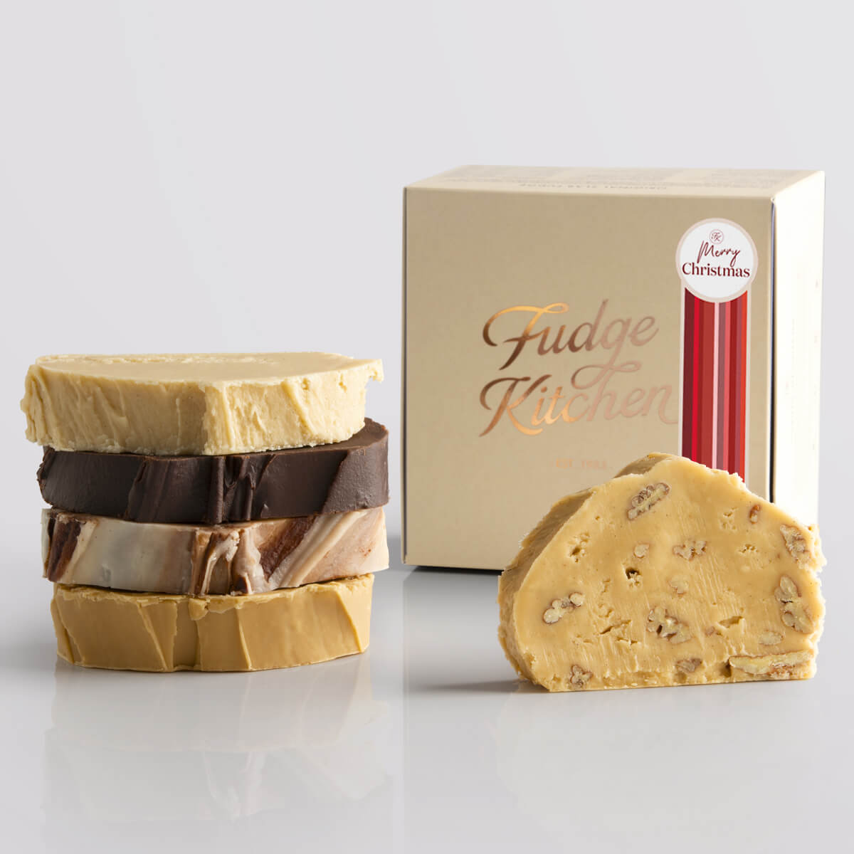 Vegan Slab Fudge Selection by Fudge Kitchen, features a collection of indulgent, handcrafted vegan fudge slabs in a variety of delicious flavours. Elegantly packaged in a buff gift box and a Merry Christmas decorative seal, ideal for gifting or enjoying as a plant-based treat.