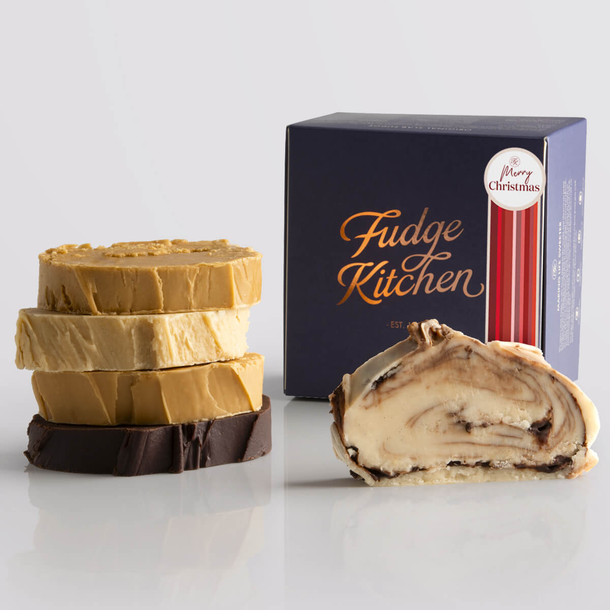 Nuts not included fudge selection from Fudge Kitchen featuring a variety of creamy, handcrafted fudge slabs in an assortment of nut-free fudge flavours, presented in an Indigo gift box and a Merry Christmas decorative seal.