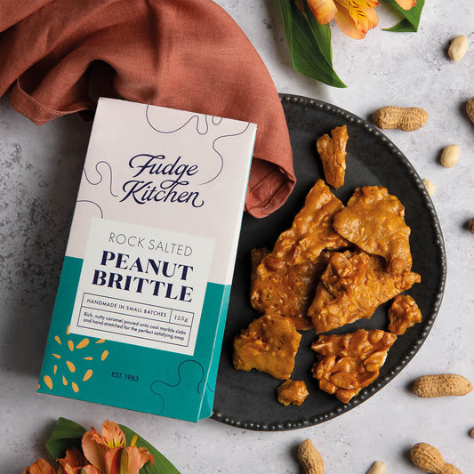 Rock Salted Peanut Brittle served on a rustic table setting. A lifestyle shot showcasing this nutty, crunchy treat for any occasion.