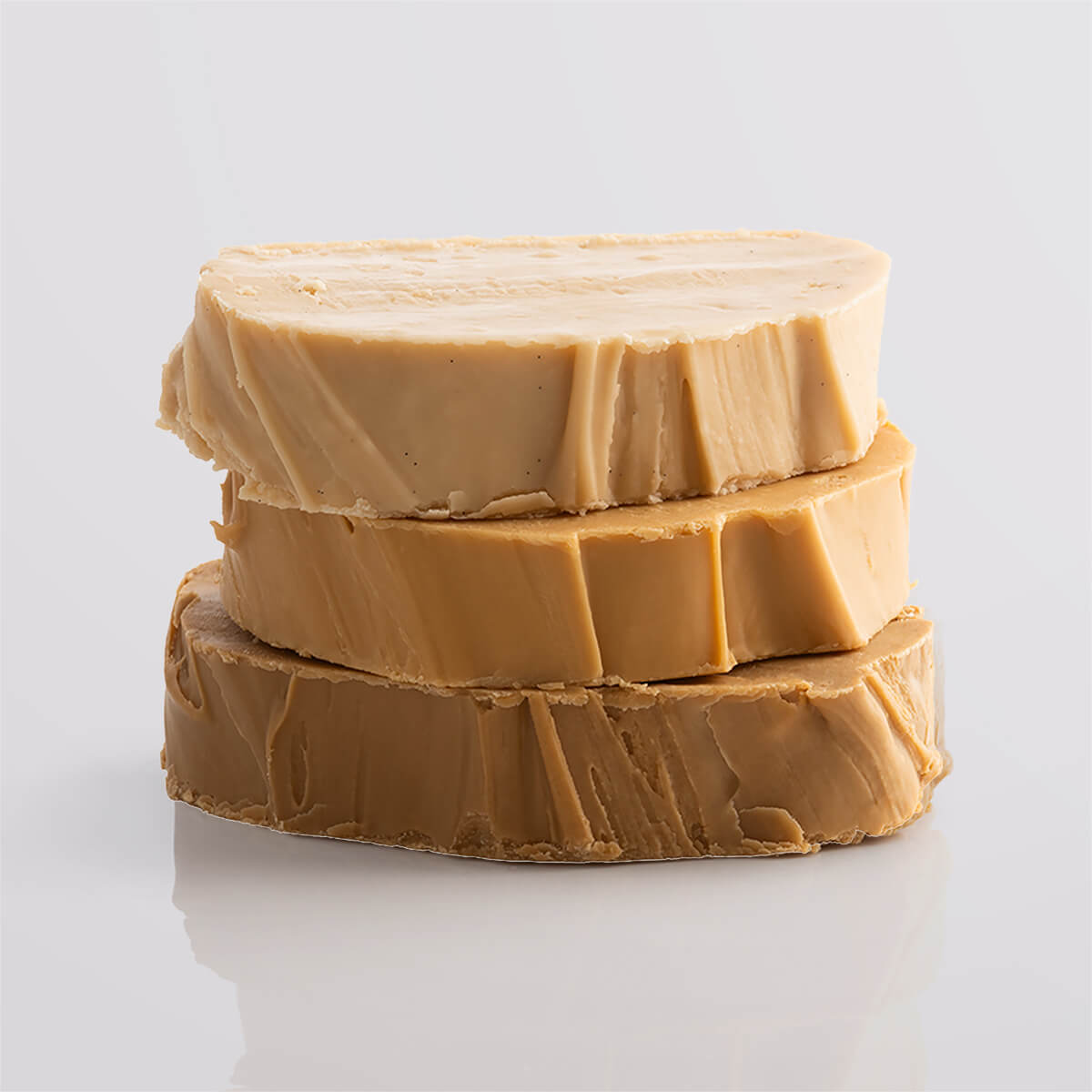 A stack of three creamy fudge slices in caramel hues, highlighting their rich and smooth texture.