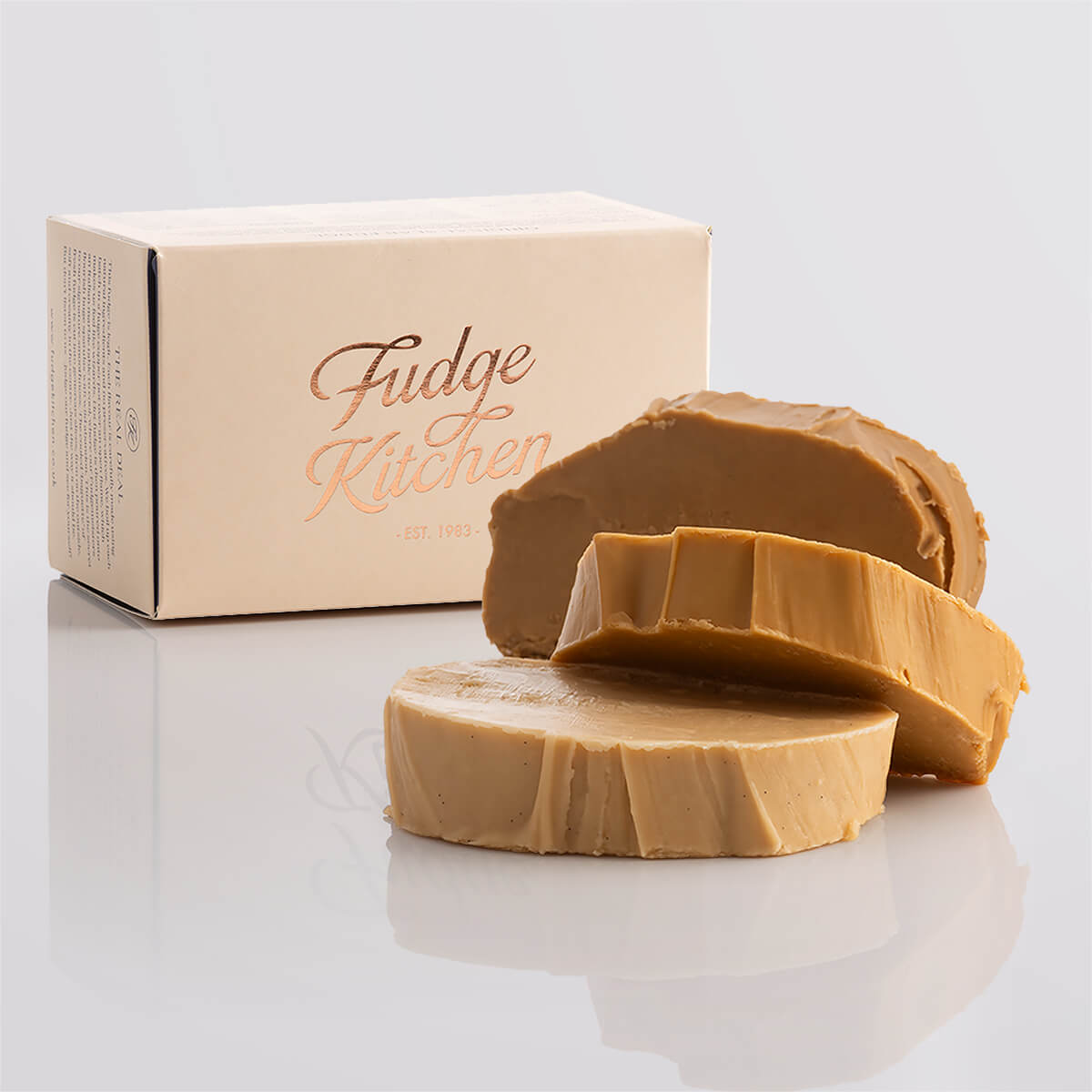 A stack of creamy caramel fudge in an elegant buff-coloured gift box with gilded accents.