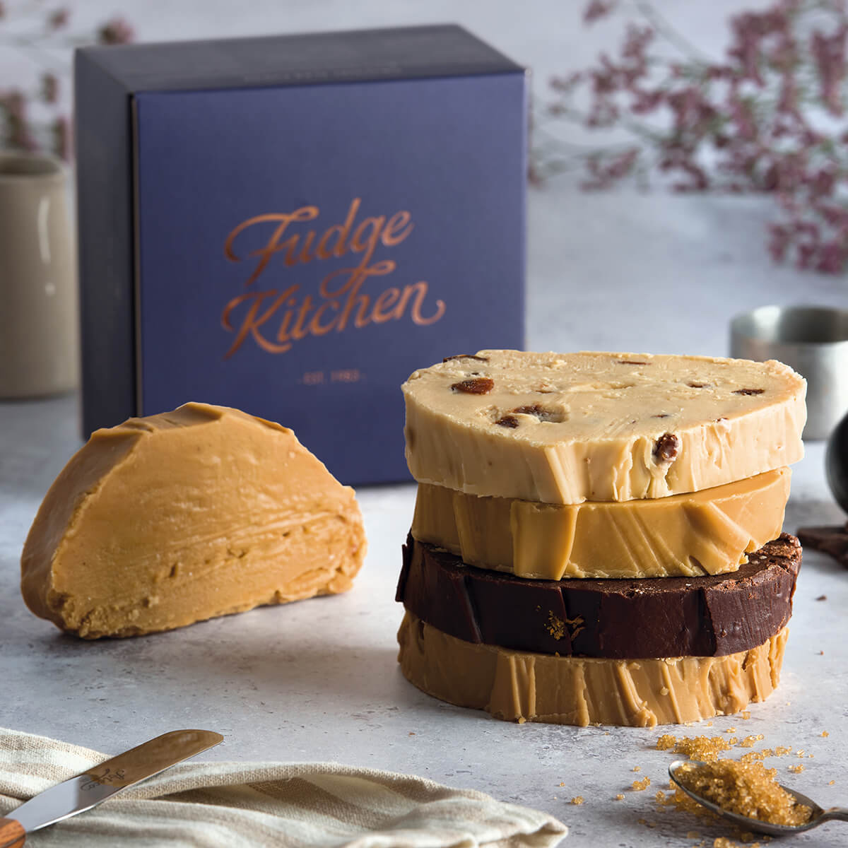 Vegan Slab Fudge Selection by Fudge Kitchen, featuring a collection of indulgent, handmade vegan fudge slabs in a variety of delicious flavours presented on a table. Elegantly packaged in an indigo gift box, ideal for gifting or enjoying as a plant-based treat.